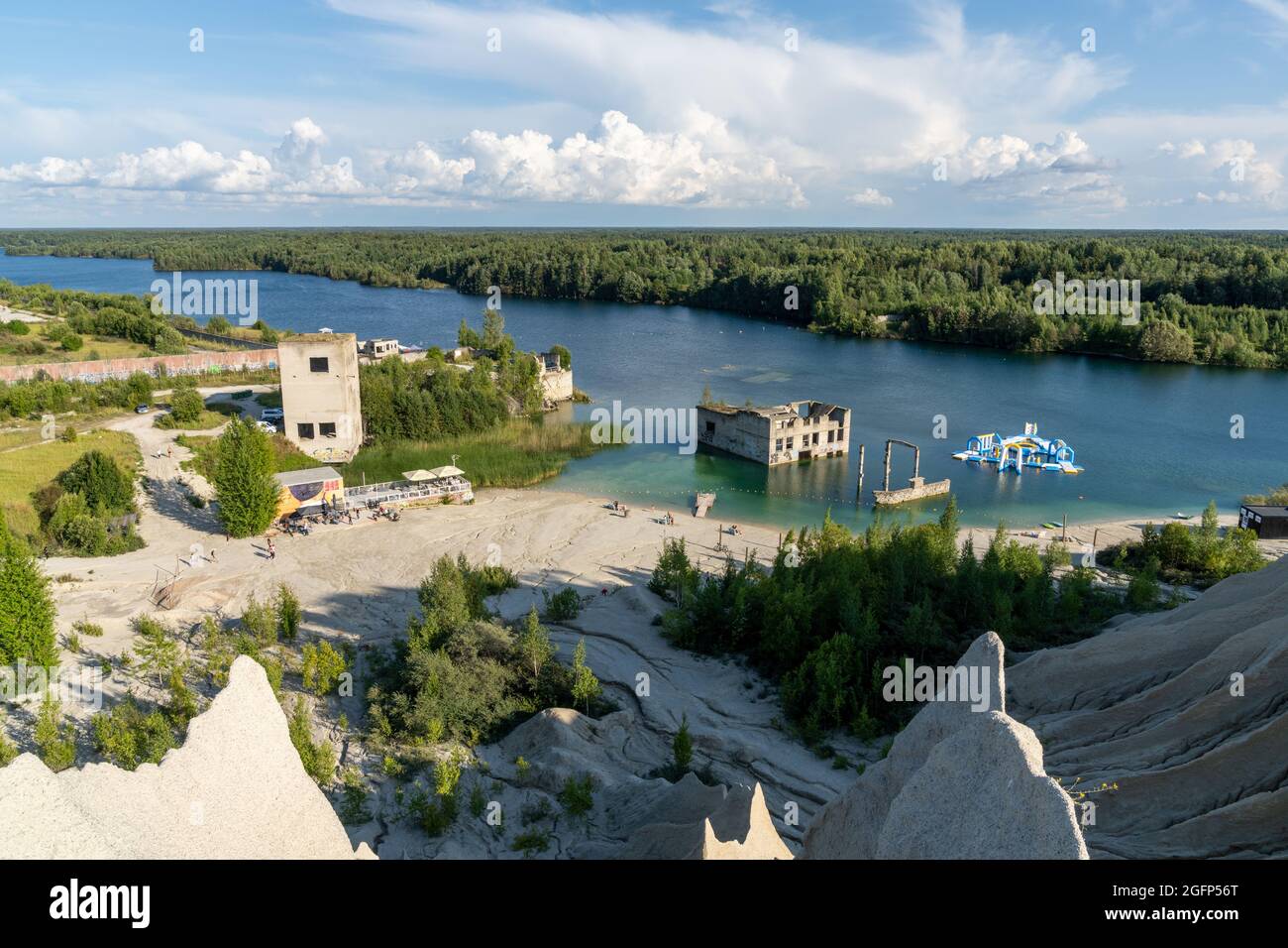 Rummu, Estonie - 12 août 2021 : montagnes calcaires et lac d'eau souterraine bleu calme dans une ancienne carrière avec des bâtiments abandonnés dans l'eau Banque D'Images