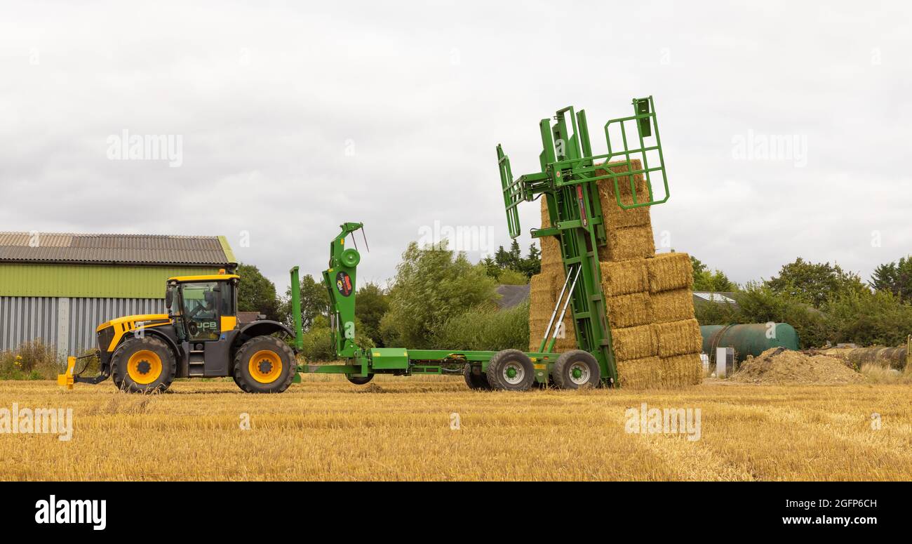 Un Bale Chaser empilant des balles de paille en position dans un champ. Hertfordshire. ROYAUME-UNI Banque D'Images