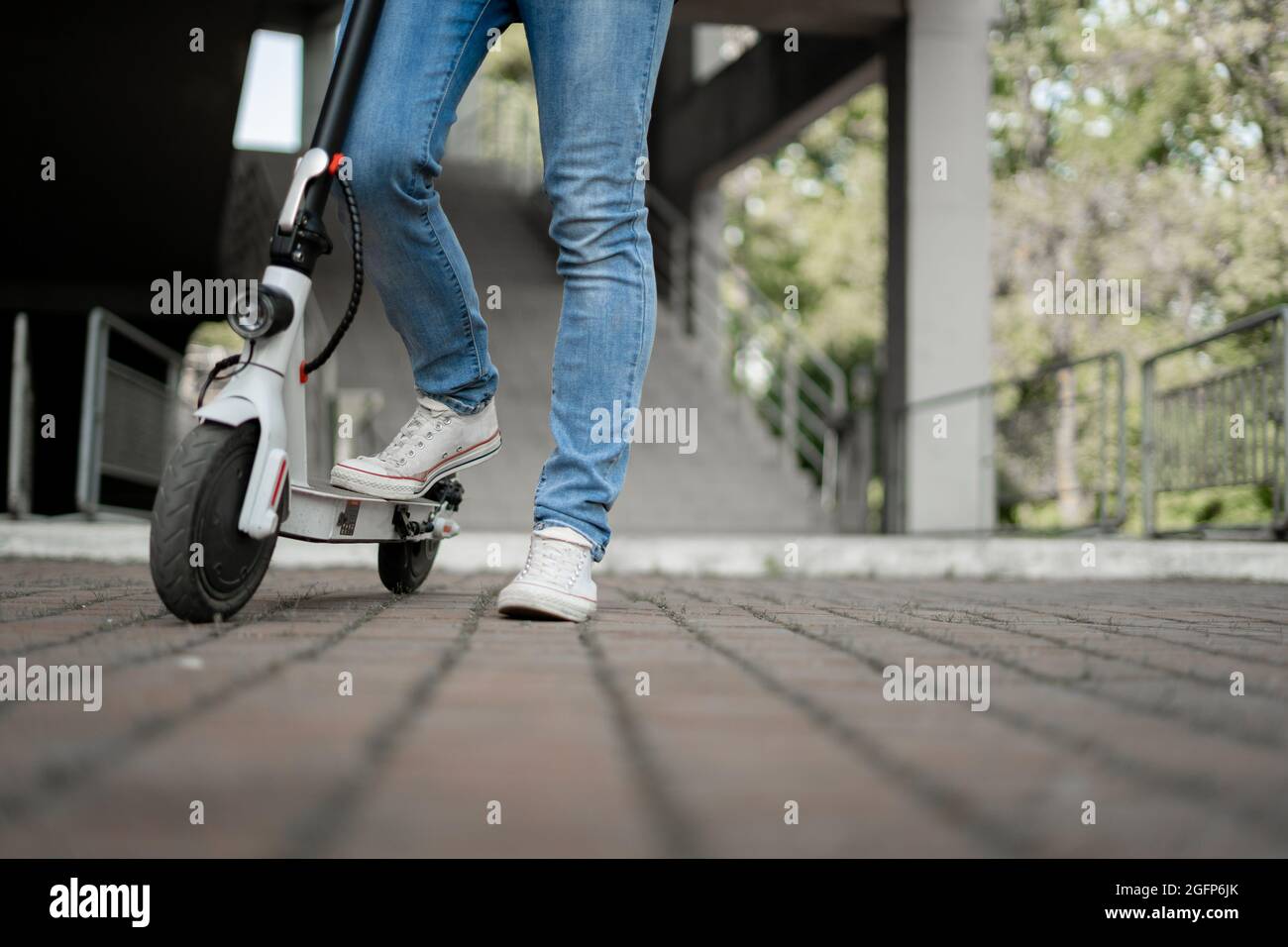 nouvelle génération de scooter électrique dans la ville près d'un centre commercial, gros plan de jambes de sexe masculin dans les baskets et les jeans, Banque D'Images