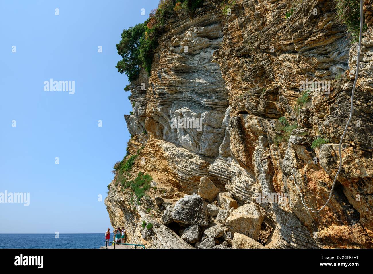 Haut mur de rochers stratifiés au-dessus du sentier vers la plage de Mogren à Budva, Monténégro. Banque D'Images