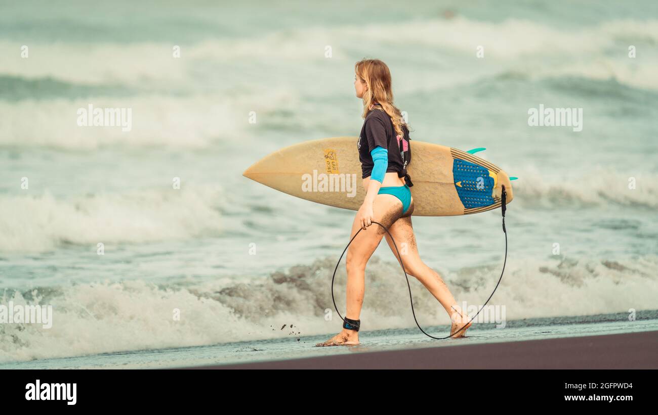 Playa Hermosa, Guanacaste, Costa Rica - 07.26.2020: Une jeune femme de race blanche marche vers la mer et porte un bateau de surf Banque D'Images