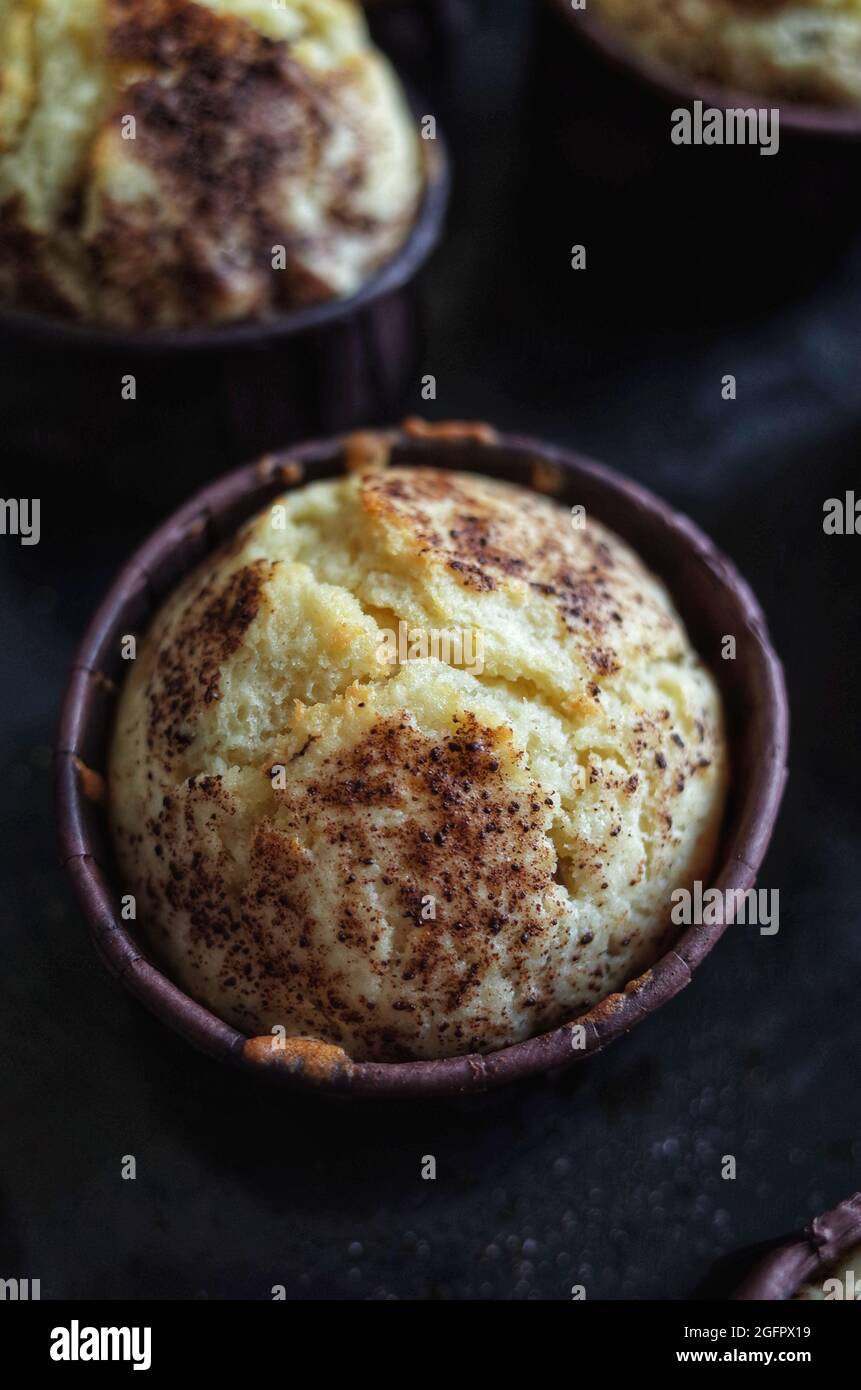Muffin à la vanille et poussière de chocolat sous de petites formes brunes, cuisine maison Banque D'Images