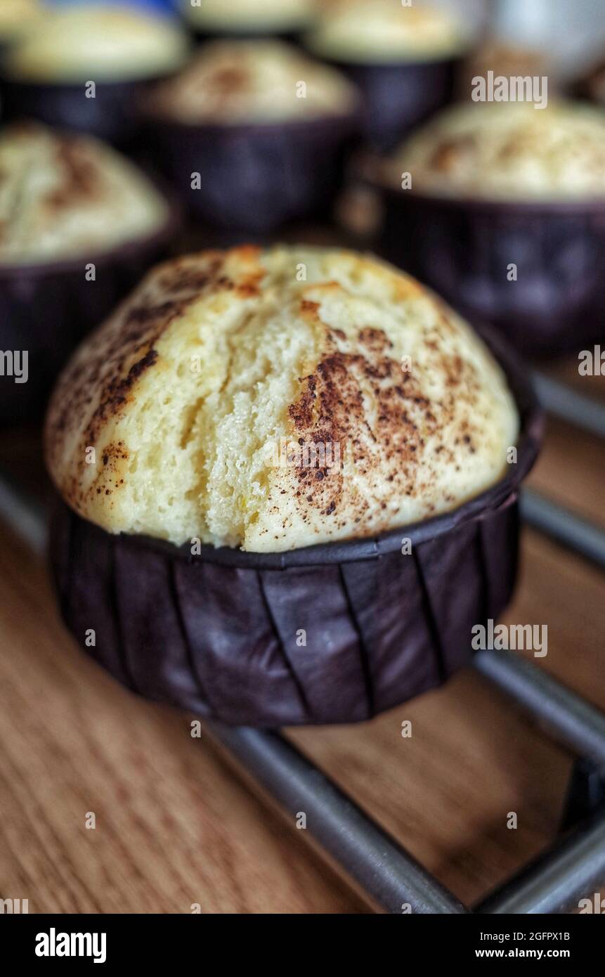 Muffin à la vanille et poussière de chocolat sous de petites formes brunes, cuisine maison Banque D'Images