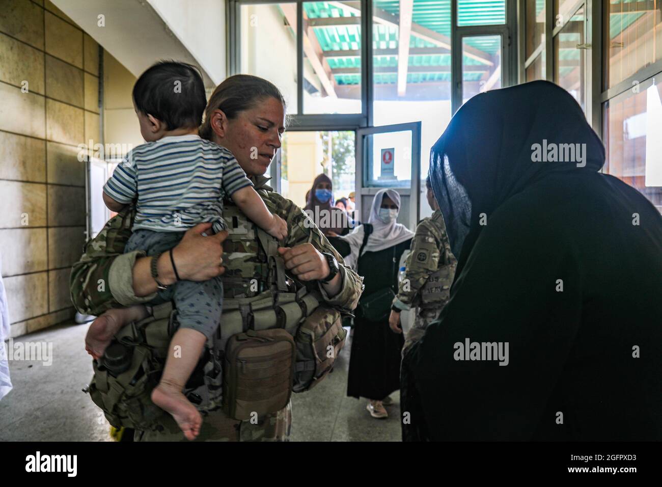 Kaboul, Afghanistan. 25 août 2021. Un soldat américain de la 82e division aéroportée, aide et femme et enfant afghans lorsqu'ils sont évacués à l'aéroport international de Hamid Karzaï lors du refuge de l'opération alliés le 25 août 2021 à Kaboul, en Afghanistan. Credit: Planetpix/Alamy Live News Banque D'Images