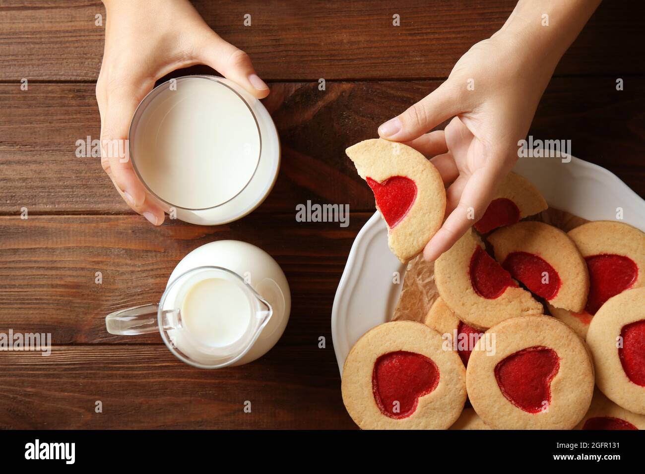 Mains féminines avec lait et biscuits sur table en bois, vue de dessus Banque D'Images