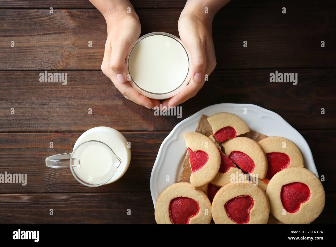 Mains féminines avec lait et biscuits sur table en bois, vue de dessus Banque D'Images