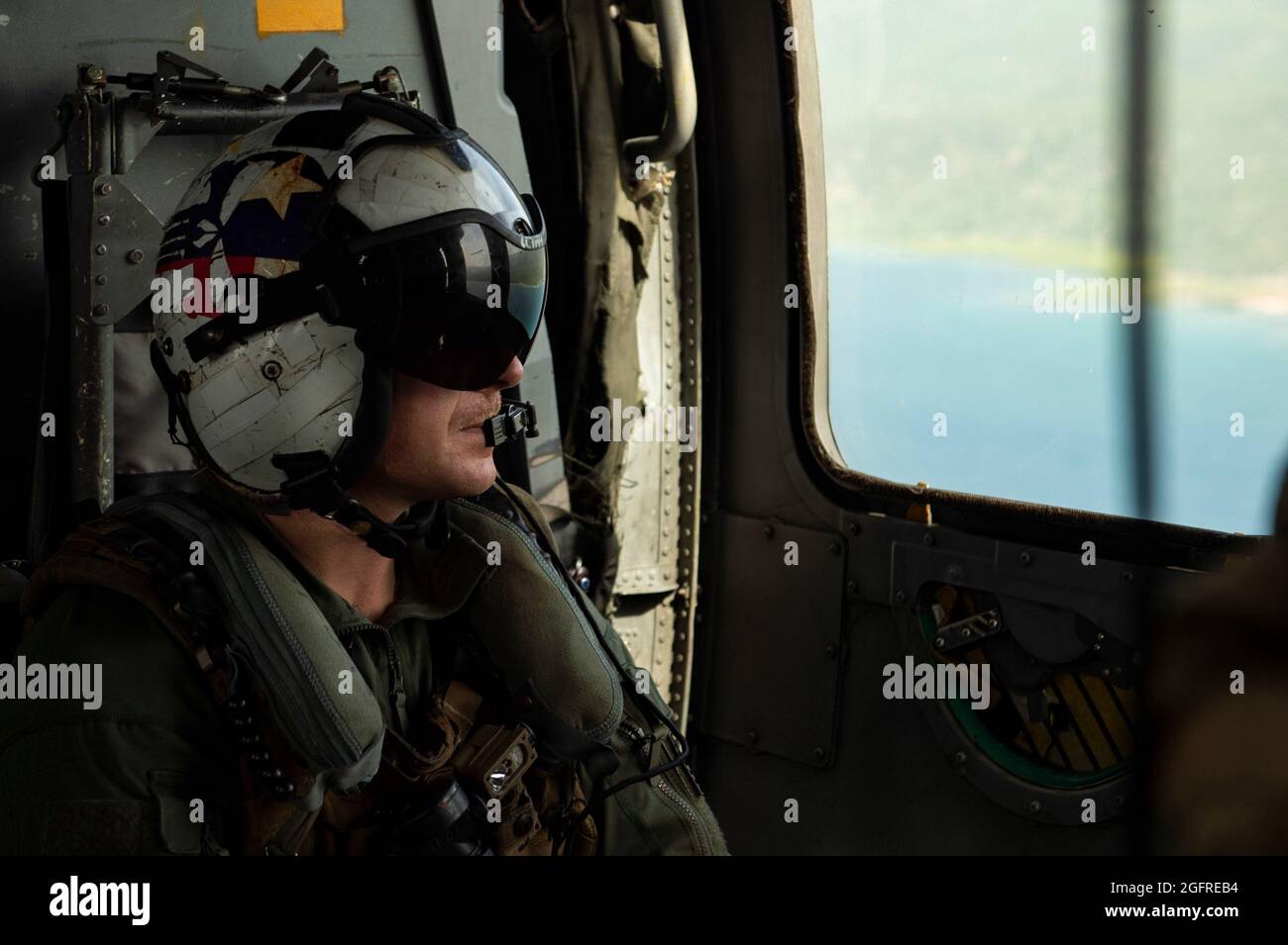 210825-N-MD802-1817 MER DES CARAÏBES - (AOÛT 25, 2021) — Naval Aircrewman (hélicoptère) Cody Christian de 1ère classe, affecté aux “Chargers” de l'Escadron de combat de la mer d'hélicoptère (HSC) 26, regarde le littoral haïtien lors d'une mission d'aide humanitaire qui soutient l'Agence américaine pour le développement international (USAID) pour fournir de la nourriture au peuple haïtien, le 25 août 2021. HSC-26 est attaché au quai de transport amphibie de classe San Antonio USS Arlington (LPD 24). Arlington est déployé au Commandement Sud des forces navales américaines/États-Unis 4ème flotte pour soutenir l'aide humanitaire et les secours en cas de catastrophe (HADR) Banque D'Images