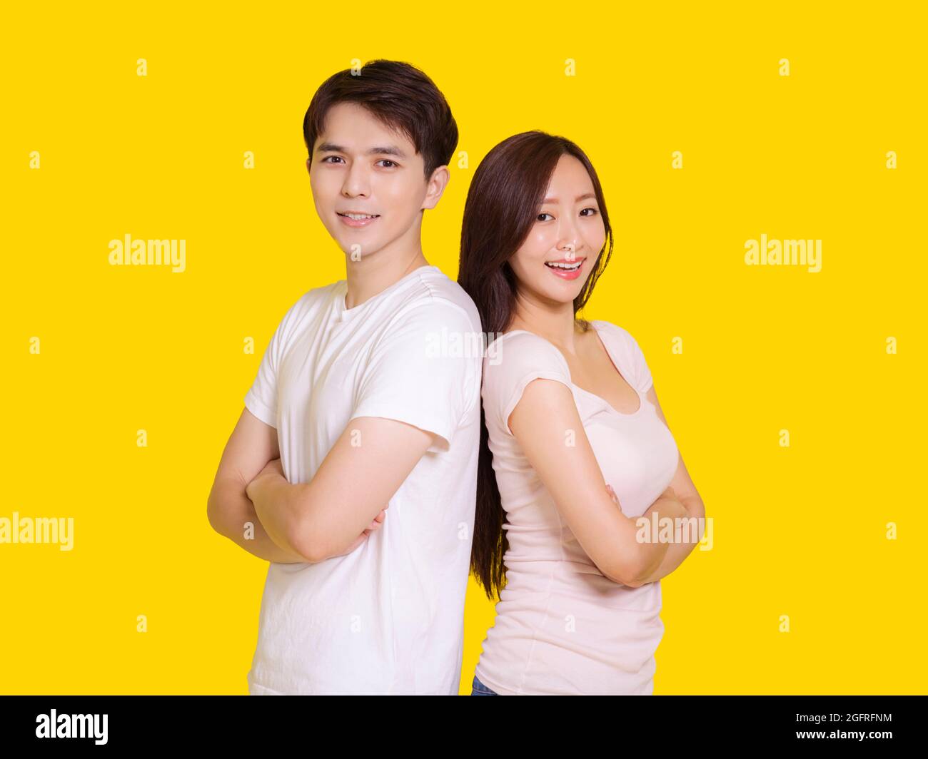 Jeune couple debout dos à dos..isolé sur fond jaune. Banque D'Images