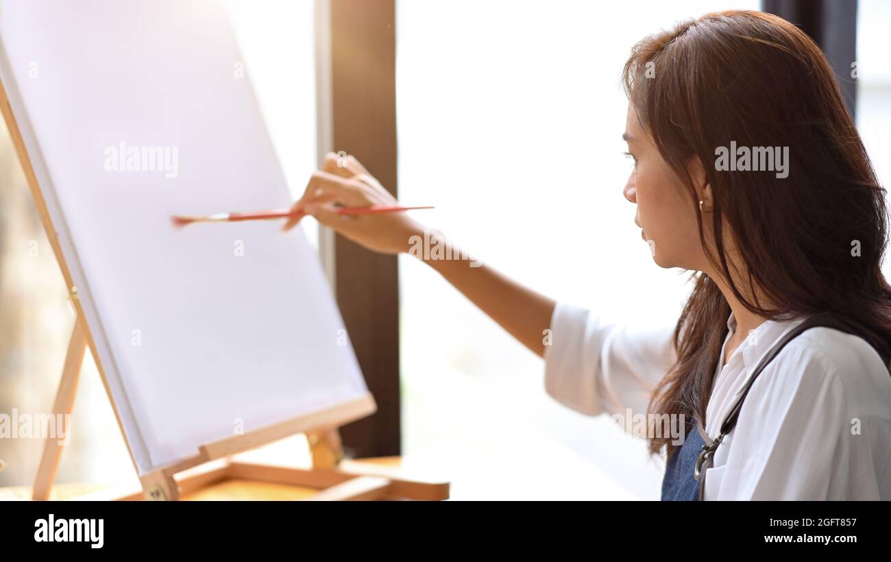 Gros plan, artiste féminine commencer à peindre sur toile vierge sur chevalet avec passion, créateur, peintre Banque D'Images