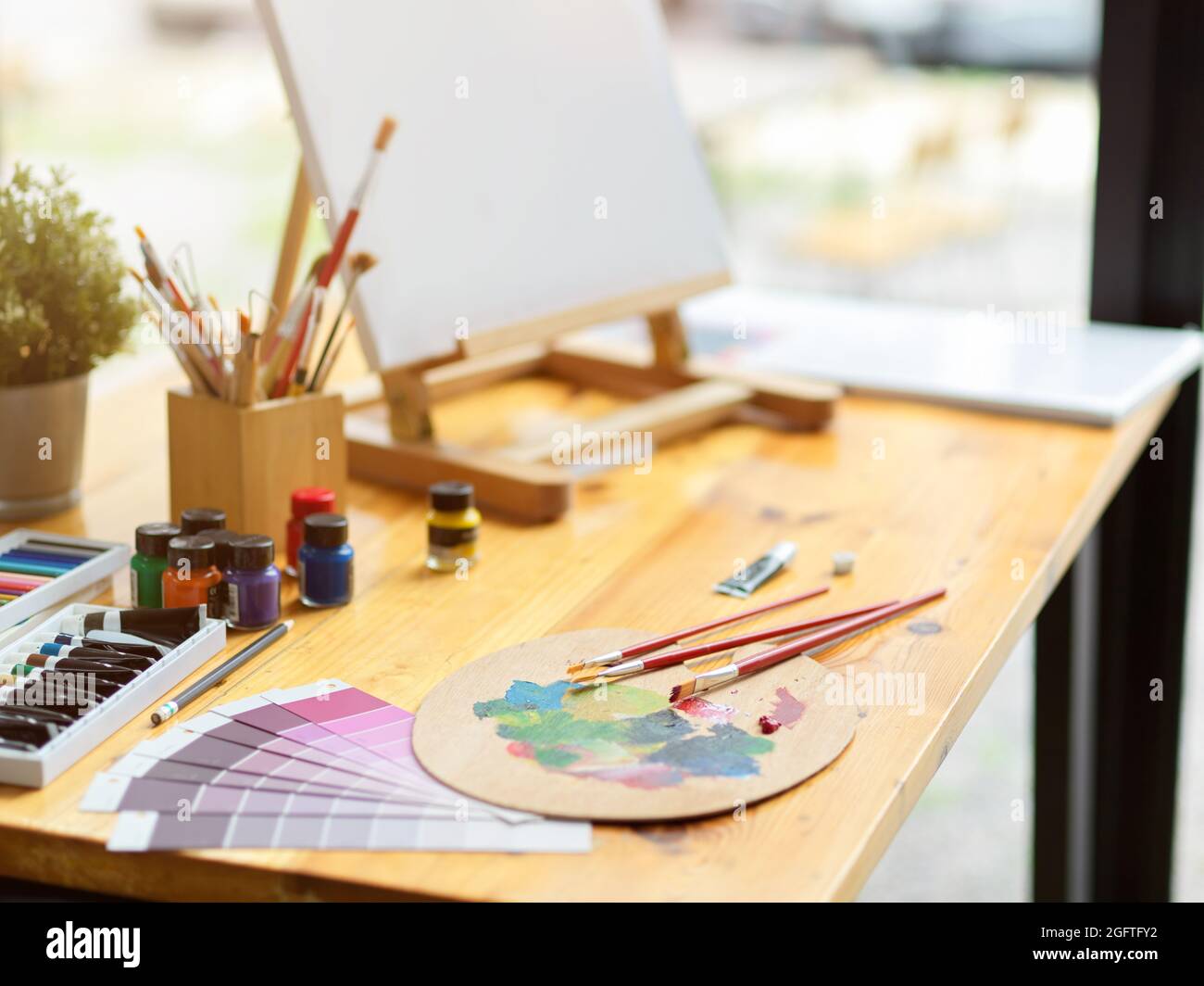 Gros plan, espace de travail artiste avec chevalet de toile, palette, pinceaux, échantillon de nuance de couleur, crayons pastel, couleur acrylique sur table en bois Banque D'Images Gros plan, espace de travail artiste avec chevalet de toile, palette, pinceaux, échantillon de nuance de couleur, crayons pastel, couleur acrylique sur table en bois Banque D'Images