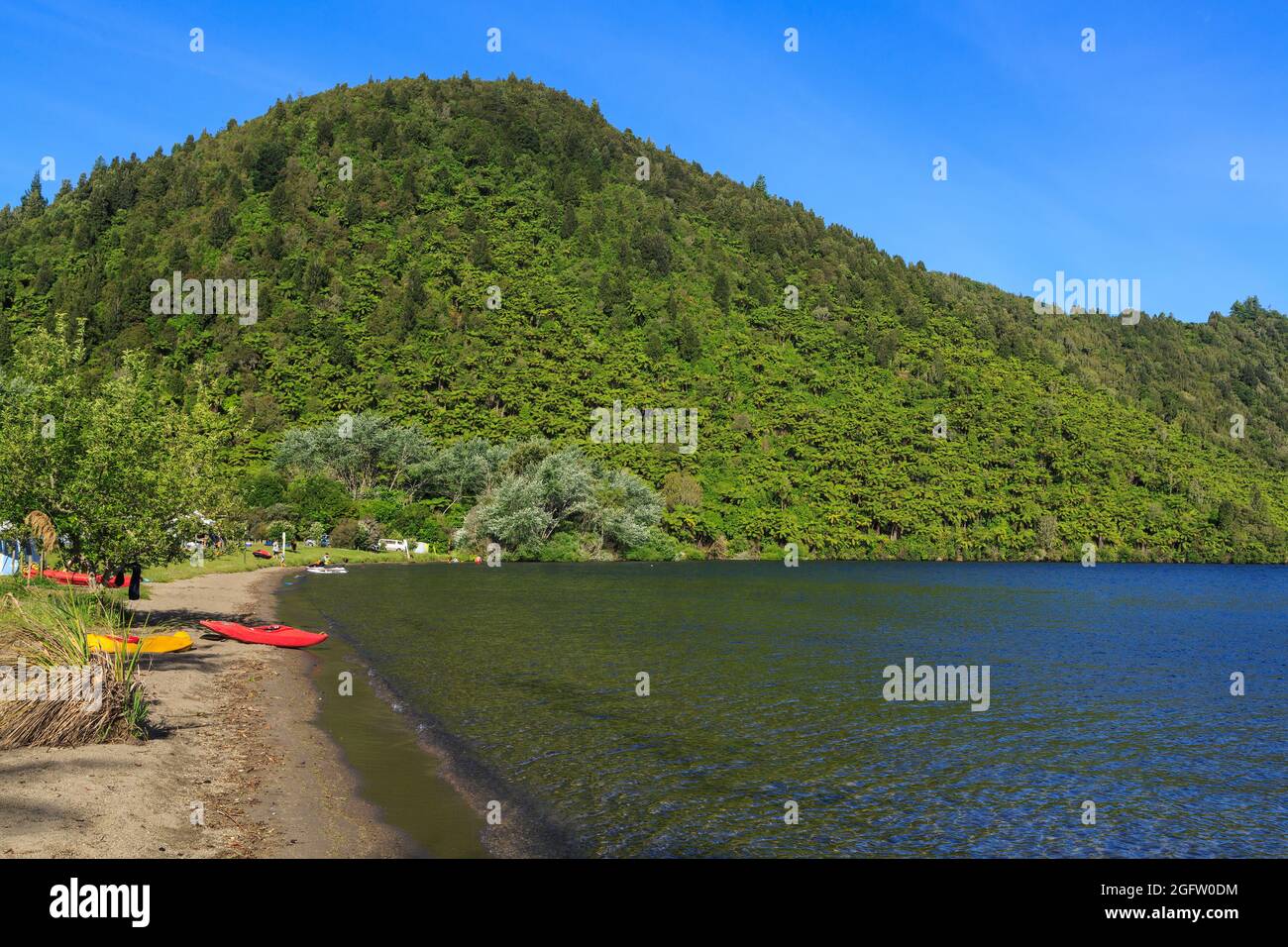 Lac Okareka dans le district des lacs de Rotorua, Nouvelle-Zélande. Les kayaks reposent sur le rivage au camping du ministère de la conservation Banque D'Images