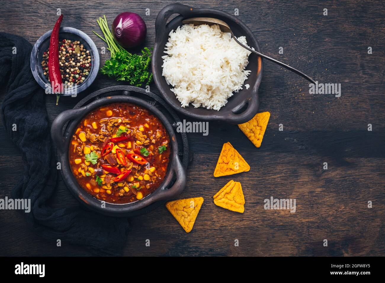 Bol de Chili con carne avec riz et garnitures sur table en bois Banque D'Images