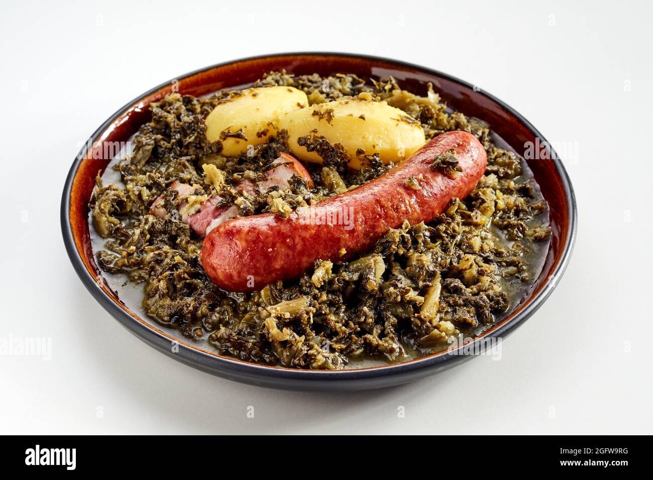 Plat allemand traditionnel de saucisse épicée et kale frais braisé riche en nutriments servi sur une assiette avec deux pommes de terre bébé dans un gros plan haut angle vi Banque D'Images