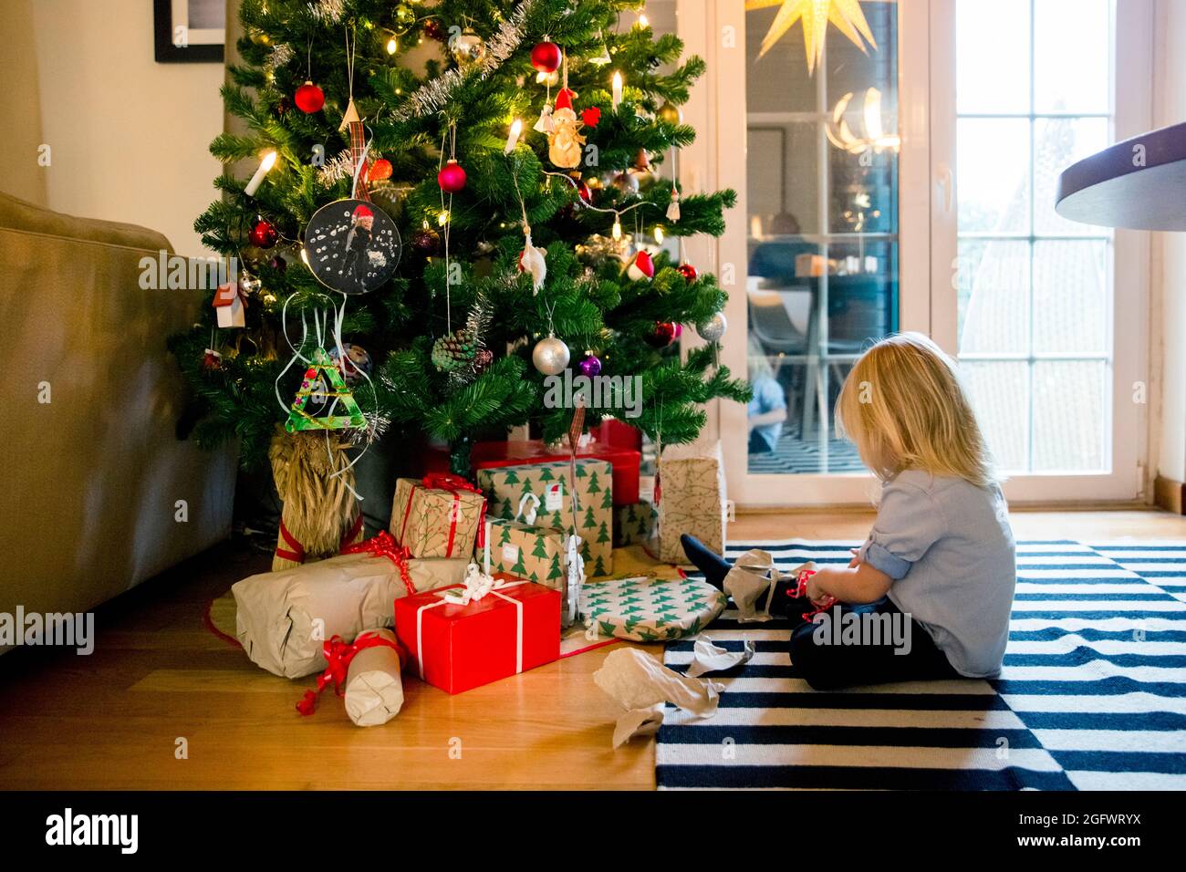 Fille assise devant l'arbre de Noël Banque D'Images