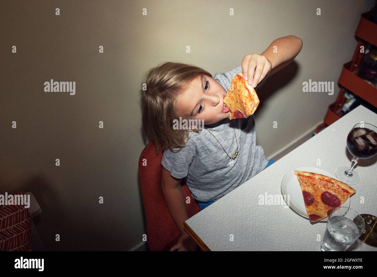 Fille à la table manger de la pizza Banque D'Images