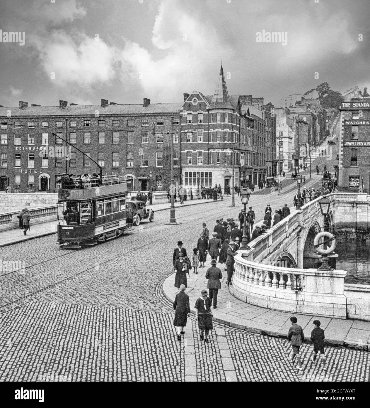 Vue du début du XXe siècle sur un tramway électrique traversant le pont Patrick au-dessus de la rivière Lee à Cork, en Irlande. Le premier pont, achevé en 1789 et incorporant un portcullis pour réglementer le trafic maritime sous le pont, a été détruit par une grave inondation en 1853. Un pont temporaire en bois, a été mis en place et le pont actuel a ouvert en 1861, reste l'un des plus célèbres monuments de Cork. Banque D'Images