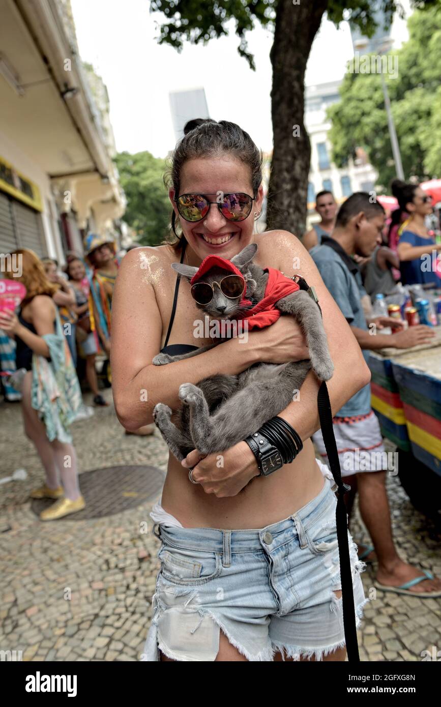 Brésil–16 février 2020 : une fille porte un chat en costume lors d'une fête  de carnaval tenue dans le centre-ville de Rio de Janeiro. Chat portant une  casquette rouge et des lunettes