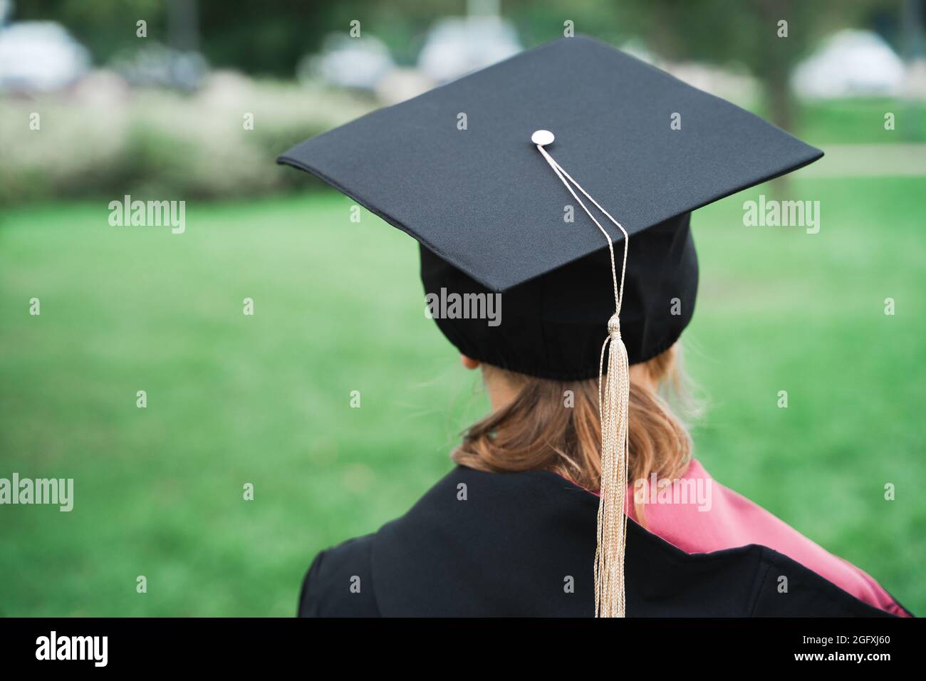 Retour au concept de l'école élémentaire. Petite fille va à la première année. Cérémonie de remise des diplômes. Robe noire, casquette universitaire avec glands. Fête avec les parents, Banque D'Images