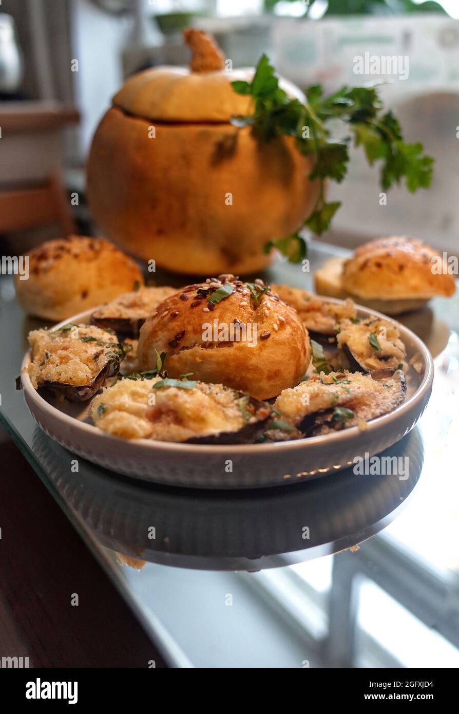 Soupe maison chaude avec moules, légumes et crème, servie dans la citrouille, avec des petits pains au sésame faits maison Banque D'Images