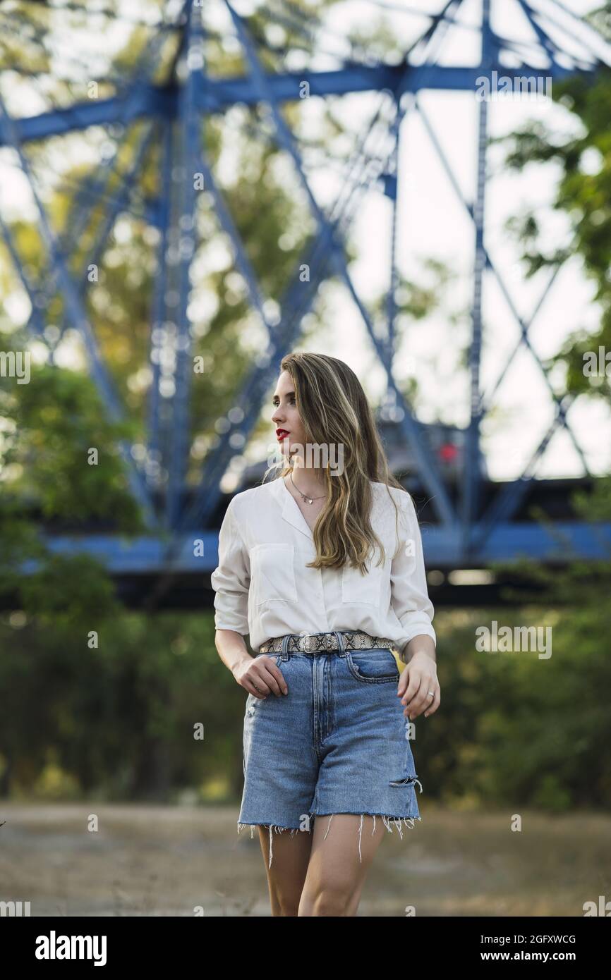 Jeune femme espagnole portant un short avec une chemise blanche et marchant  dans un parc Photo Stock - Alamy