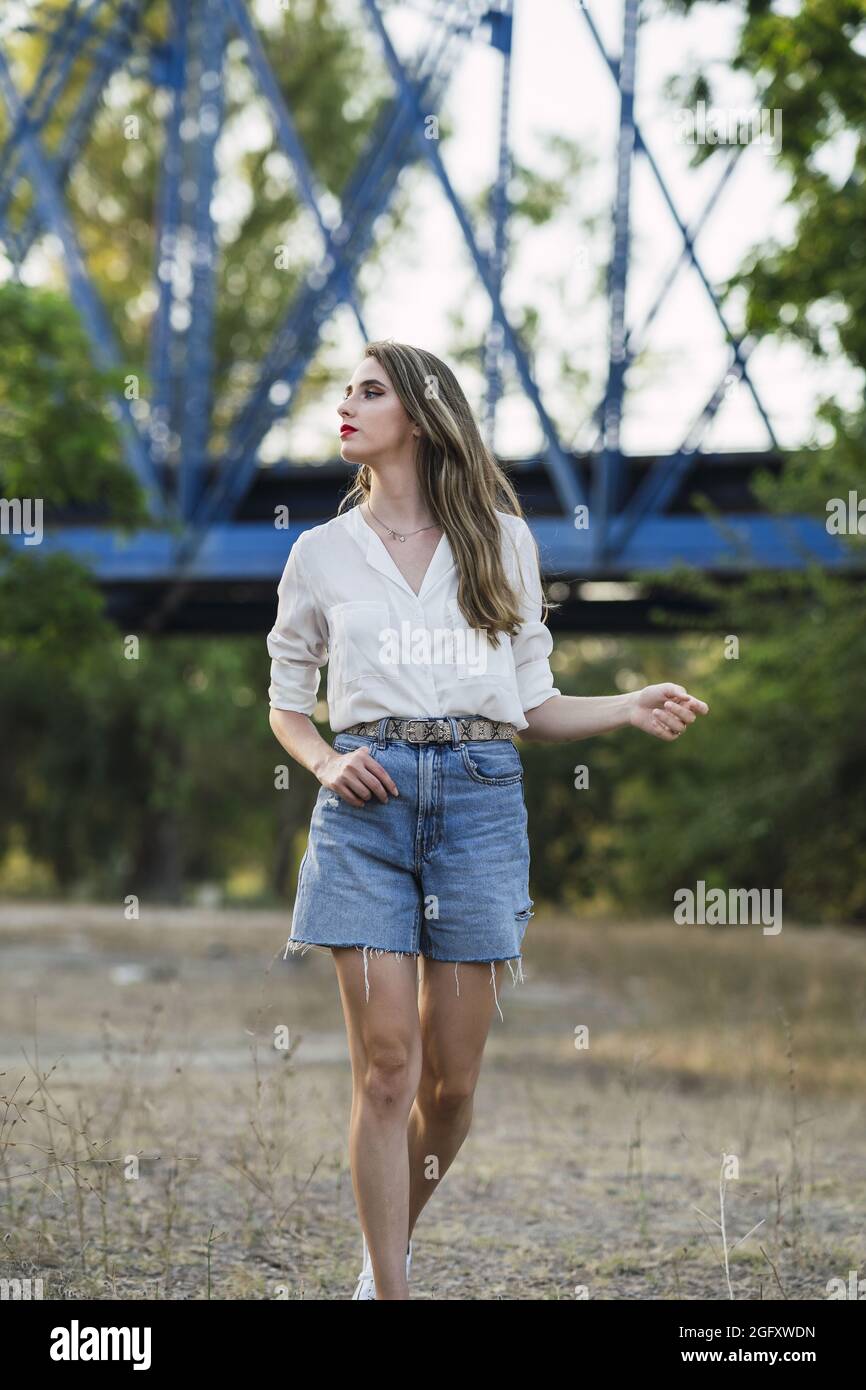 Jeune femme espagnole portant un short avec une chemise blanche et marchant  dans un parc Photo Stock - Alamy