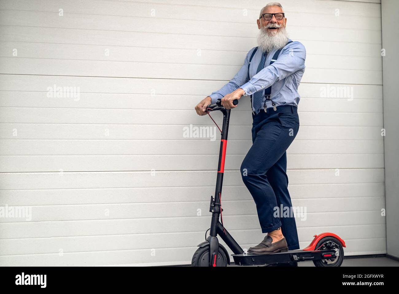 Homme d'affaires senior qui va travailler au bureau avec un scooter électrique - Eco transport concept Banque D'Images
