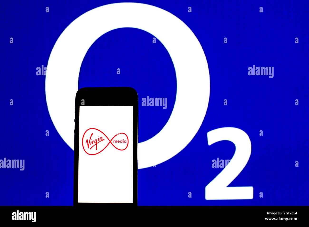 Sur cette photo, un logo Virgin Media Inc apparaît sur un smartphone avec un logo O2 en arrière-plan. Banque D'Images