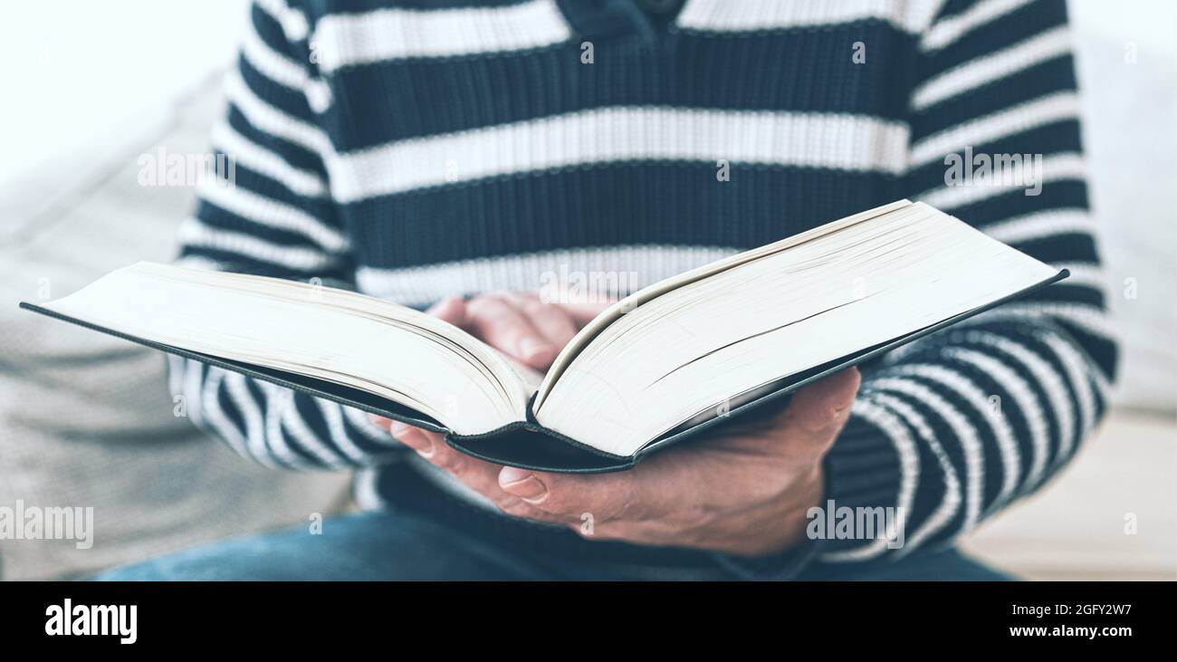 vue rapprochée d'un homme assis sur un canapé pour lire un livre Banque D'Images