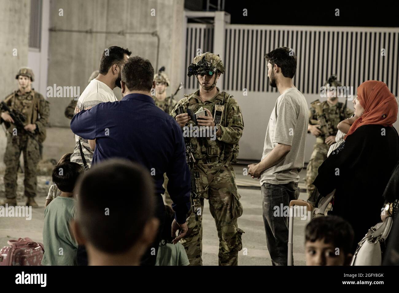 Les soldats américains de la 82e Division aéroportée aident les évacués lors d'une évacuation à l'aéroport international Hamid Karzaï, Kaboul, Afghanistan, août 25. Les membres du service américain aident le ministère d'État à effectuer une opération d'évacuation (NEO) non combattue en Afghanistan. (É.-U. Photo du corps marin par le sergent d'état-major. Victor Mancilla) Banque D'Images