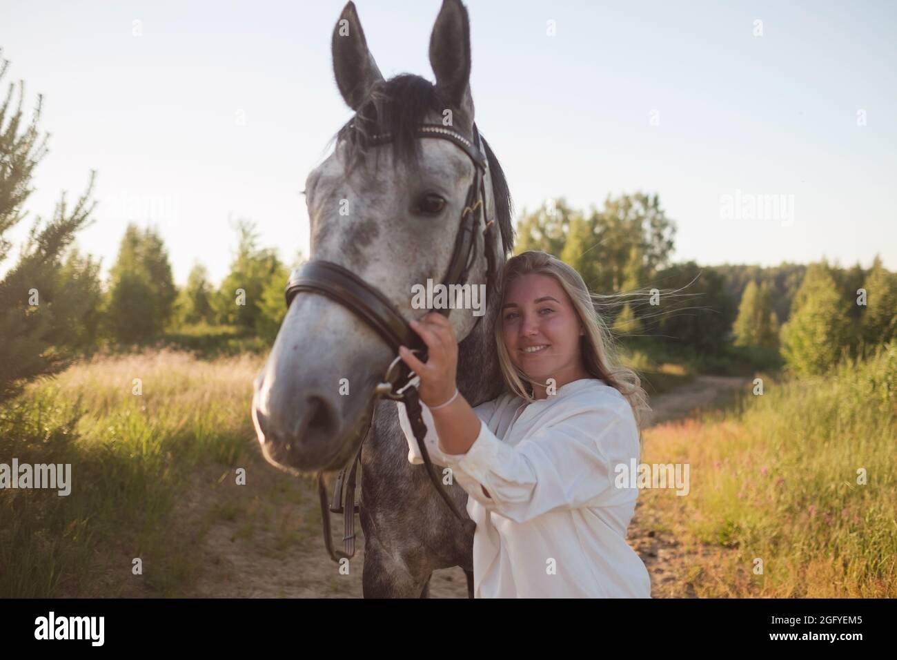 Jeune caucasienne belle femme passant du temps avec son cheval marchant sur le terrain. Banque D'Images