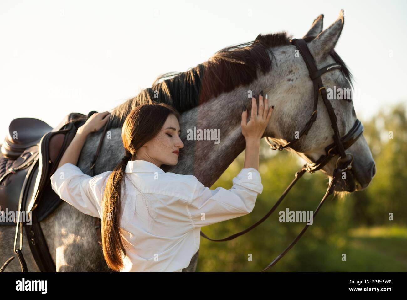 Jeune belle femme prenant soin de son cheval l'embrassant. Banque D'Images