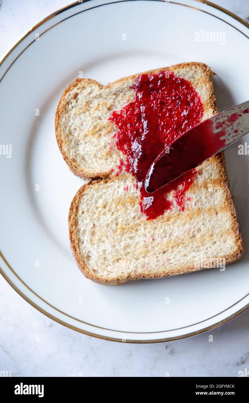 Confiture de baies rouges sur pain grillé sur plaque blanche et dorée Banque D'Images