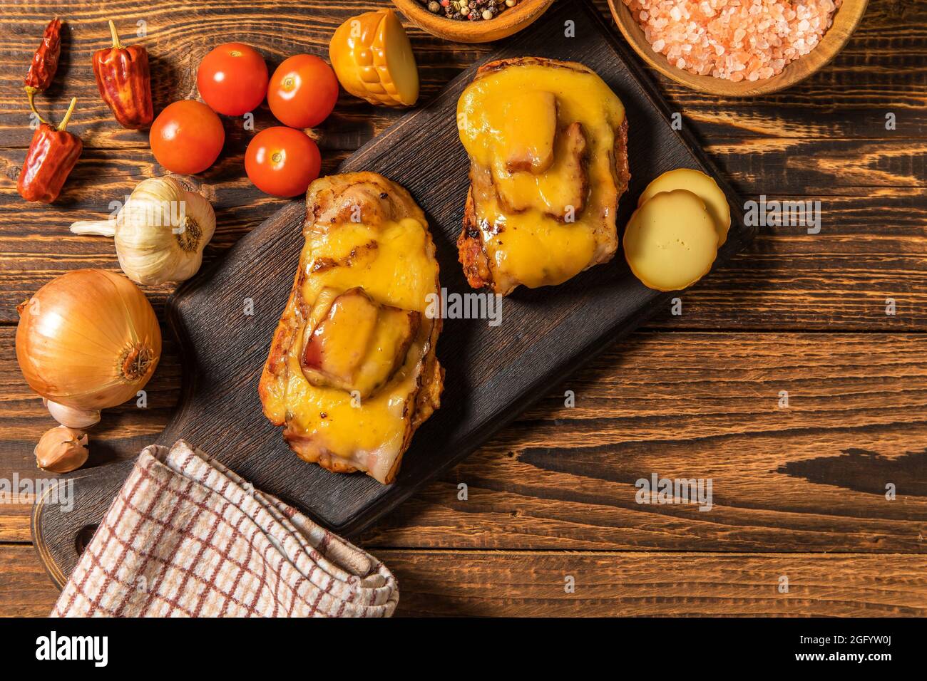 Hacher le porc mariné dans de la sauce moutarde avec du bacon et du fromage. Viande grillée au fromage. Portions de viande sur la table. Banque D'Images