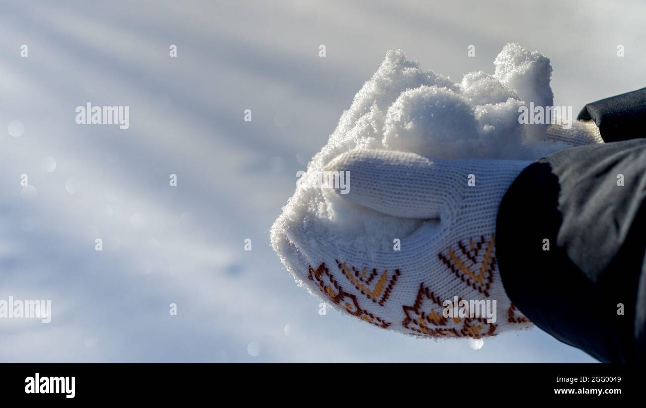 mains tenant une pile de neige blanche étincelante, portant des mitaines tricotées blanches, bannière. soleil brillant, heap lumineux mis en évidence, jour d'hiver ensoleillé, fond neigeux avec des faisceaux de lumière, cristaux de glace, flocons de neige Banque D'Images