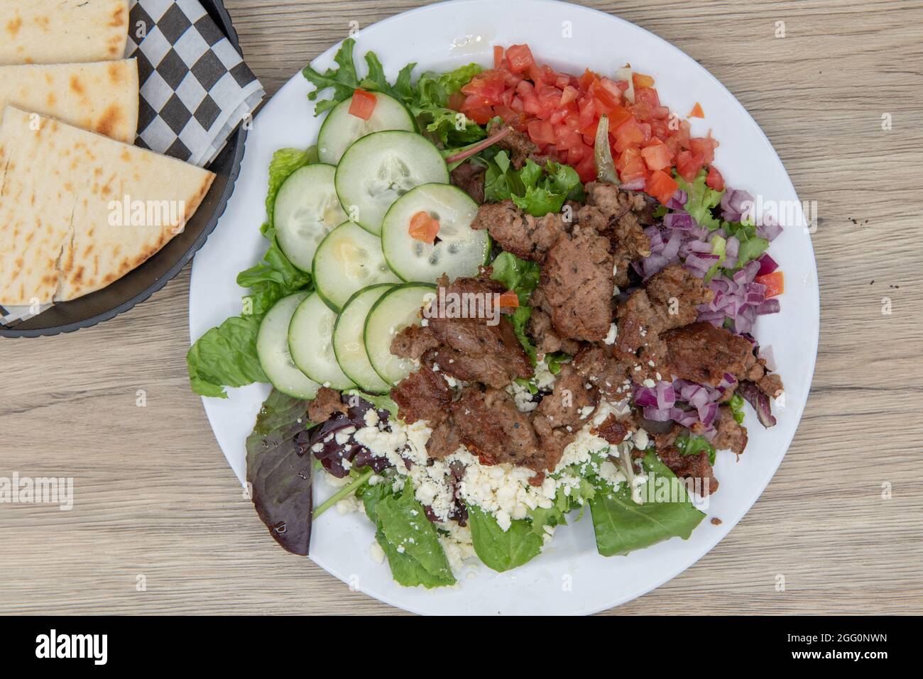 Vue de dessus des mangeurs soucieux de leur santé peuvent avoir la salade grecque chargée avec des légumes frais et servi avec des quartiers de pita. Banque D'Images