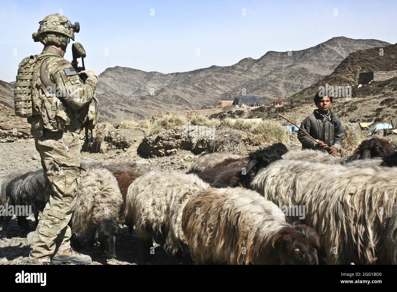 PFC de l'armée américaine. Tyler Sirovy, un fantassin de la Compagnie B, 1er Bataillon, 133e Régiment d'infanterie, 2e Brigade combat Team, 34e Division d'infanterie d'Oskaloosa, Iowa, regarde un jeune garçon passer avec un troupeau de moutons lors d'une patrouille à travers Wardachi (Afghanistan), près de la frontière entre l'Afghanistan et le Pakistan Mars 13. Banque D'Images