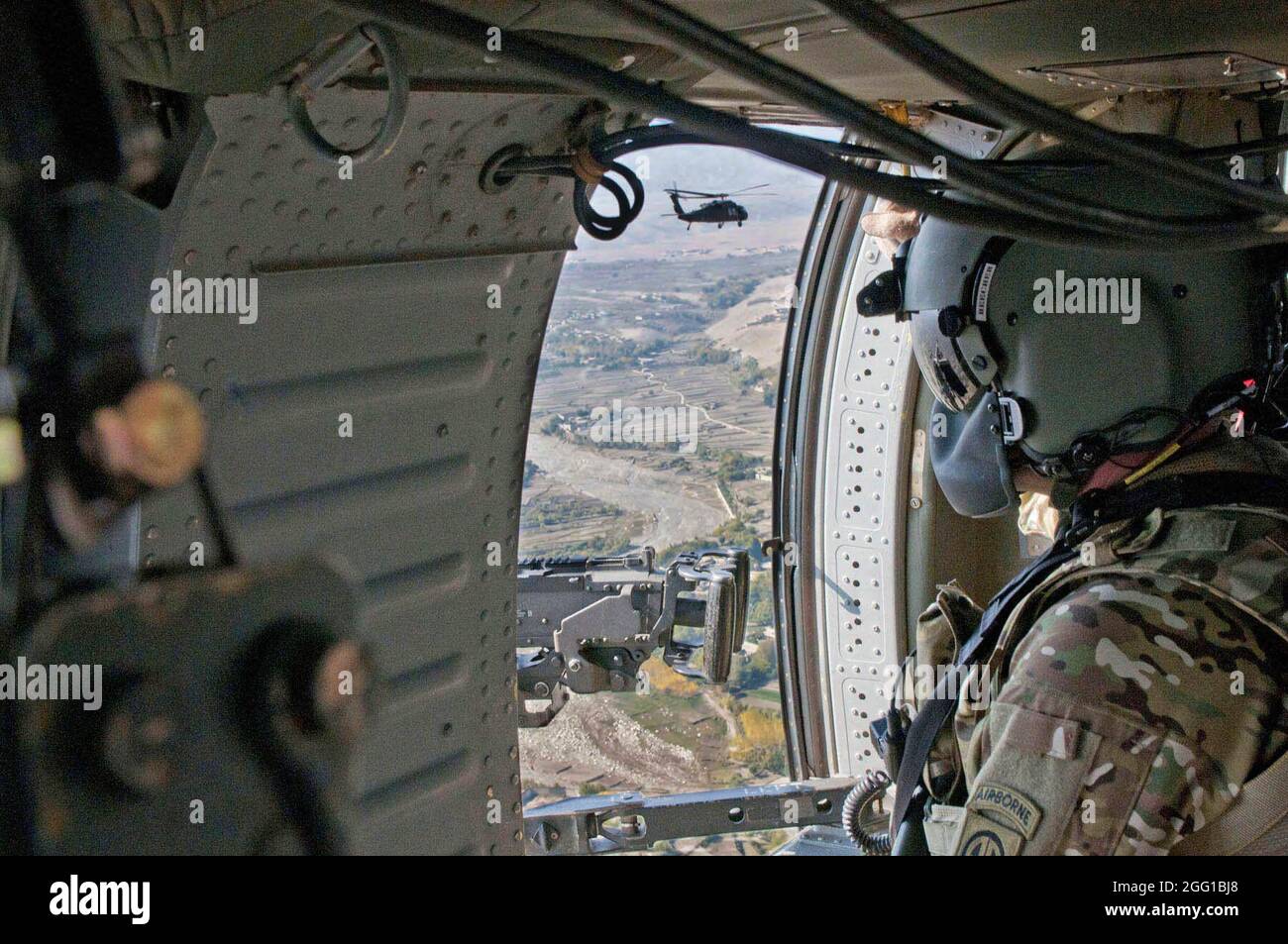 Le capitaine de l'armée américaine Tim Beecher, de St. Louis, Missouri, 82e Brigade de l'aviation de combat, est le mitrailleur à la porte d'un UH-60 Black Hawk alors qu'il et un autre Black Hawk survolent la région de Tora Bora près de la frontière du Pakistan le 5 novembre. Banque D'Images