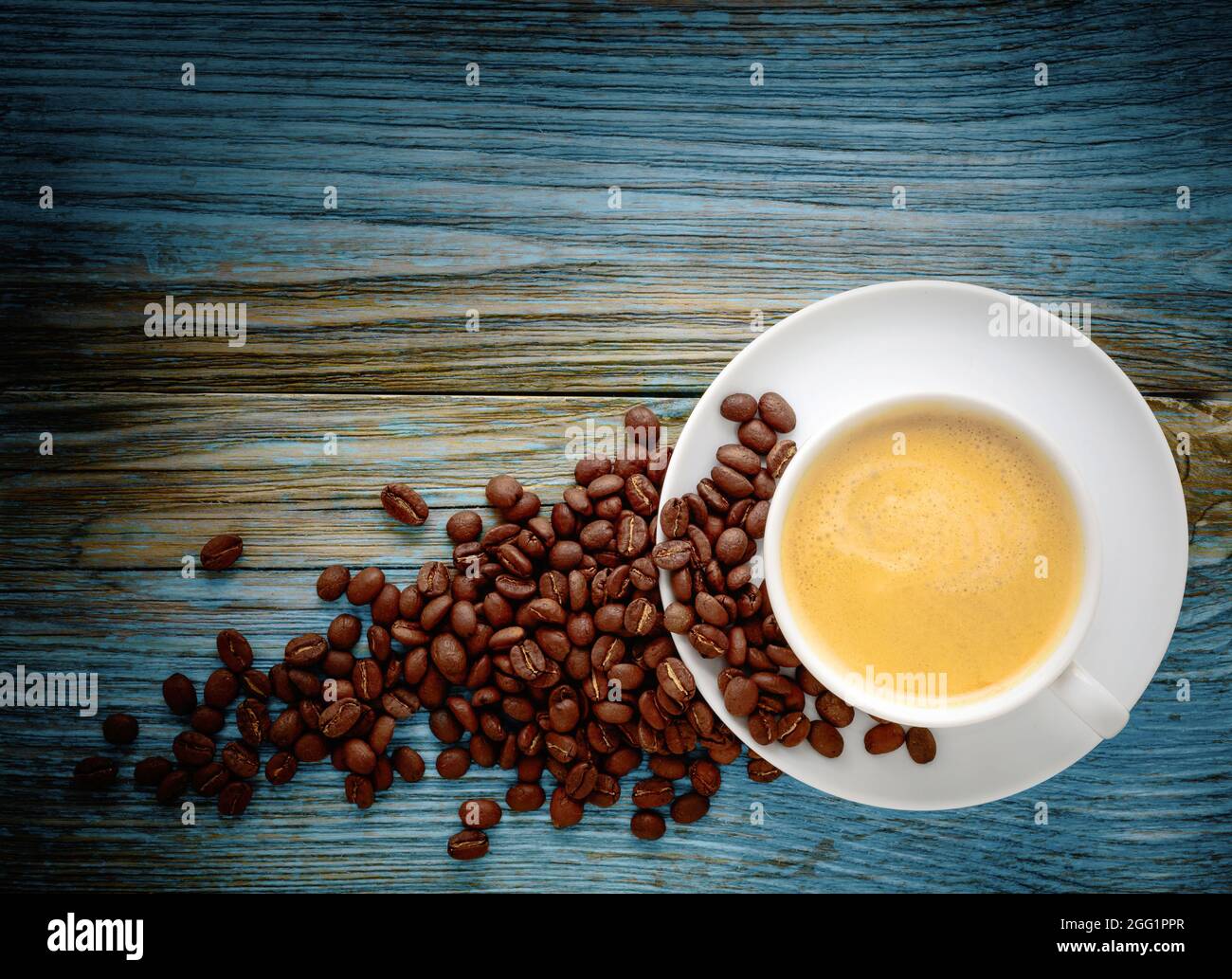 Tasse de café blanc et haricots sur fond de bois ancien. Banque D'Images