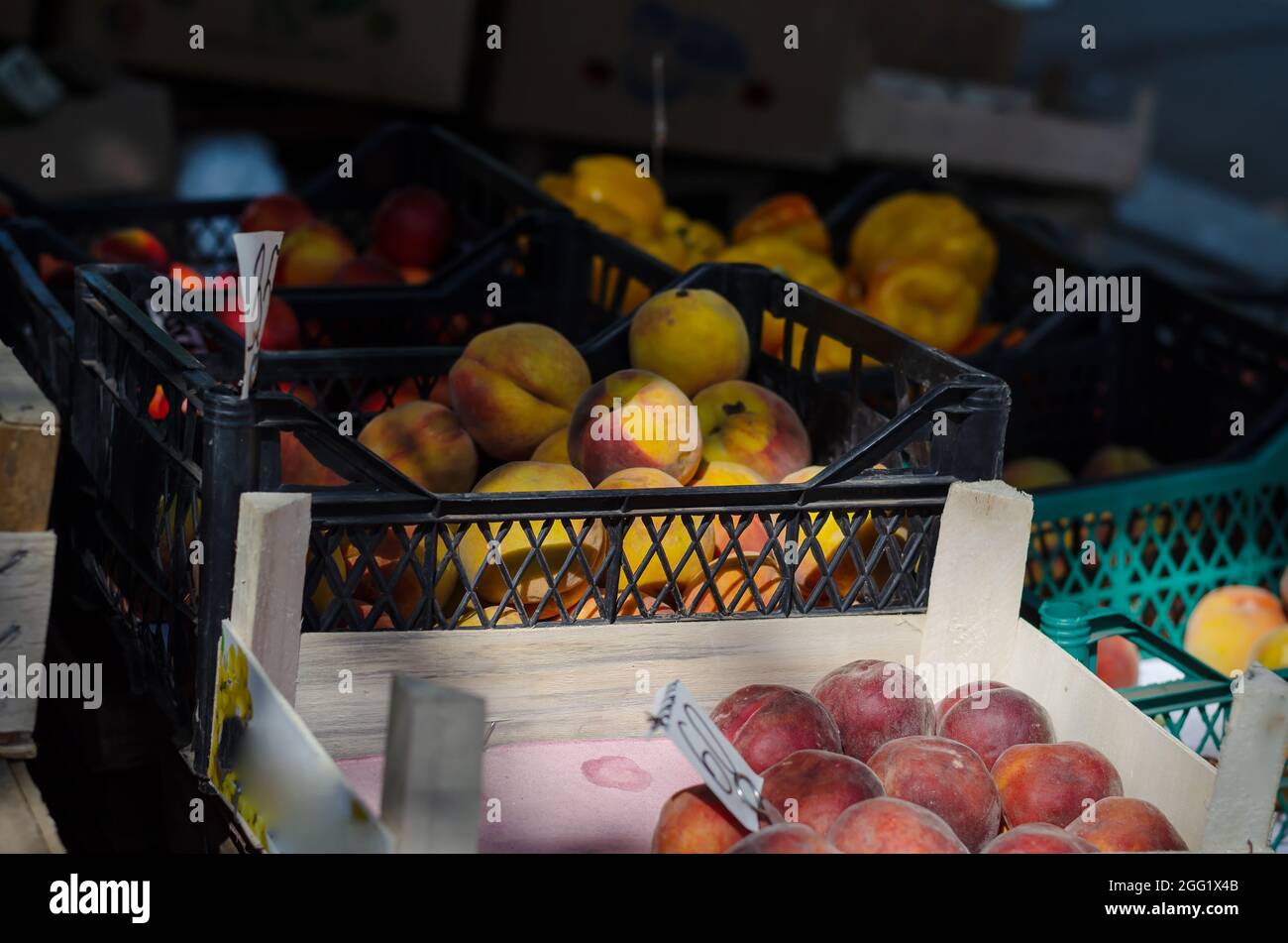 Commerce des pêches et des abricots sur le marché de rue. Les fruits mûrs sont dans des caisses en bois et en plastique. Étiquettes de prix. Mise au point sélective. Banque D'Images