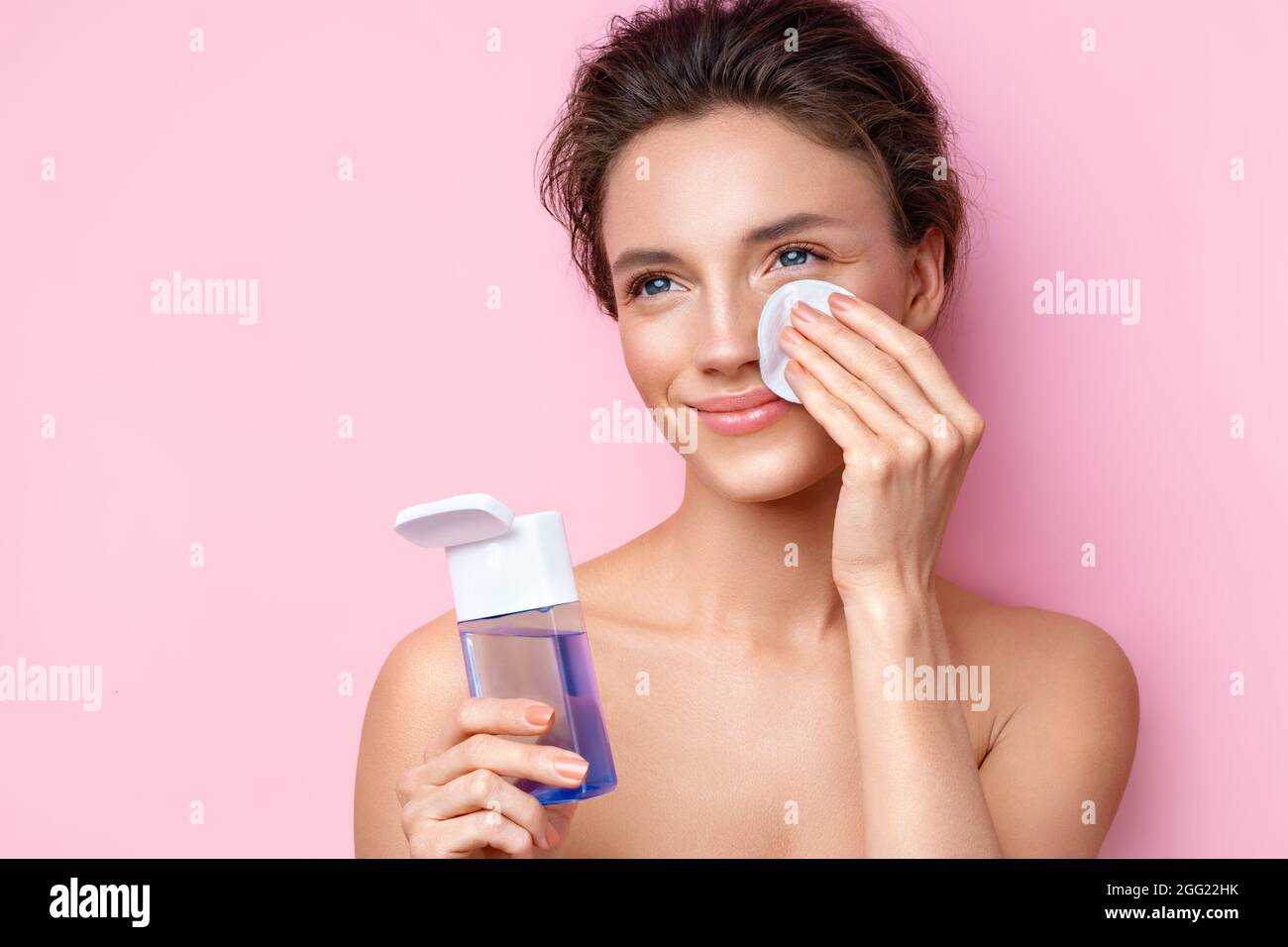Femme démaquillant, tient les tampons de coton près du visage. Photo d'une femme avec une peau parfaite sur fond rose. Beauté et soins de la peau concept Banque D'Images