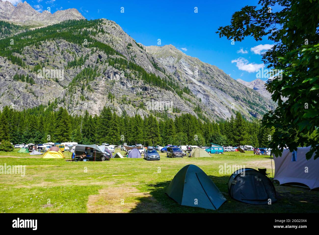 Tentes et véhicules dans les prairies d'été dans la vallée reculée d'Ailefroide, Briançon, Ecrins, France, Alpes françaises Banque D'Images