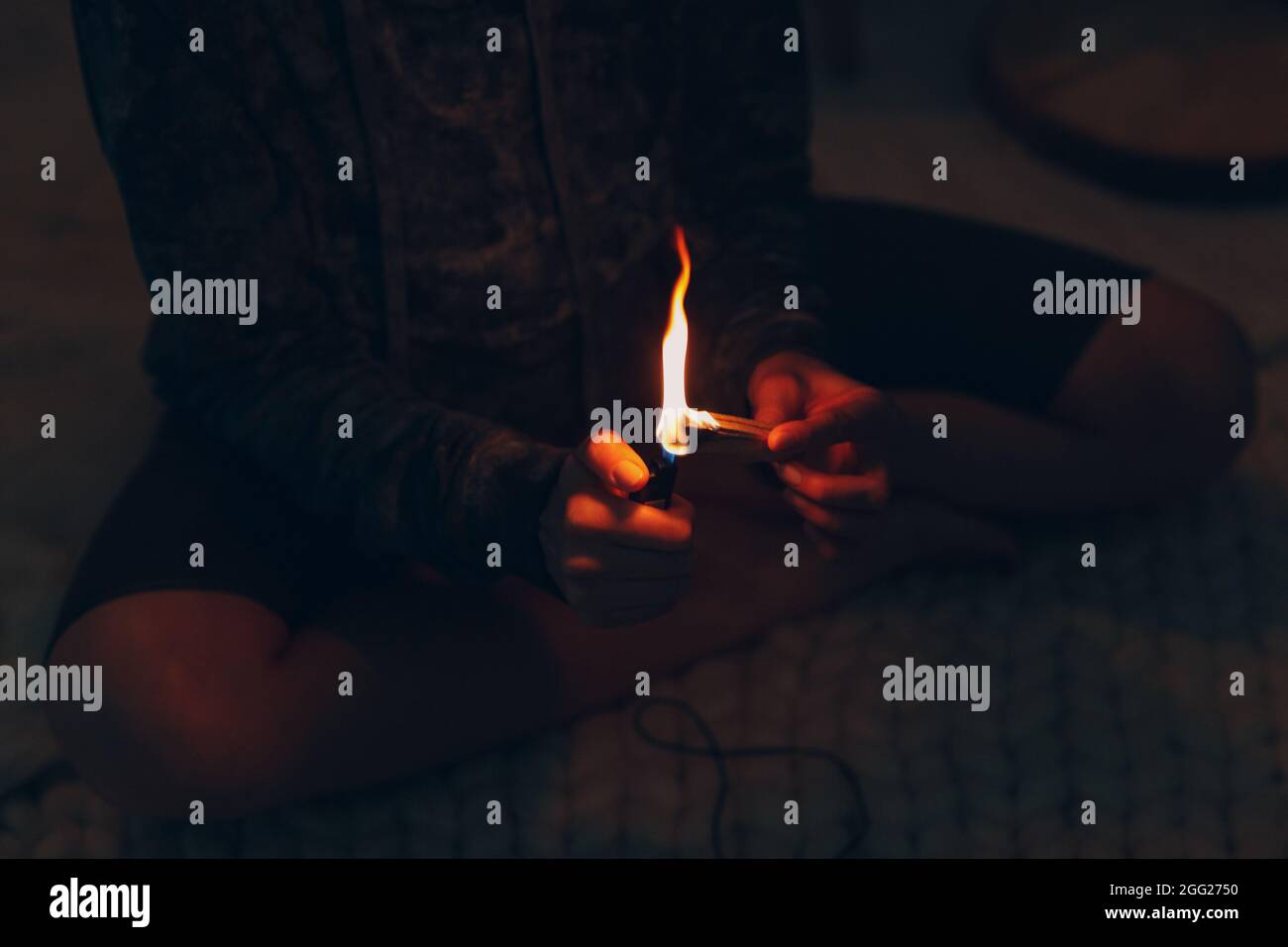 Adulte mature femme faisant du yoga à la maison salon fixe le feu avec l'arbre de bâton de palo santo Banque D'Images