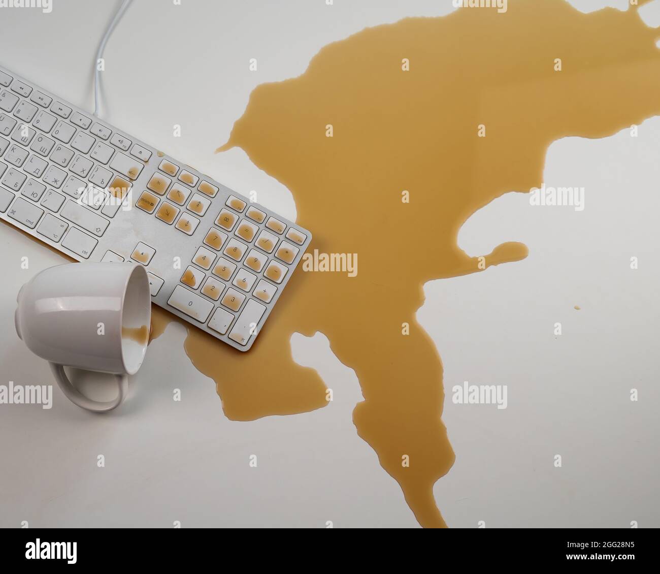Tasse de café noir renversée sur le clavier de l'ordinateur sur la table blanche. Banque D'Images Tasse de café noir renversée sur le clavier de l'ordinateur sur la table blanche. Banque D'Images