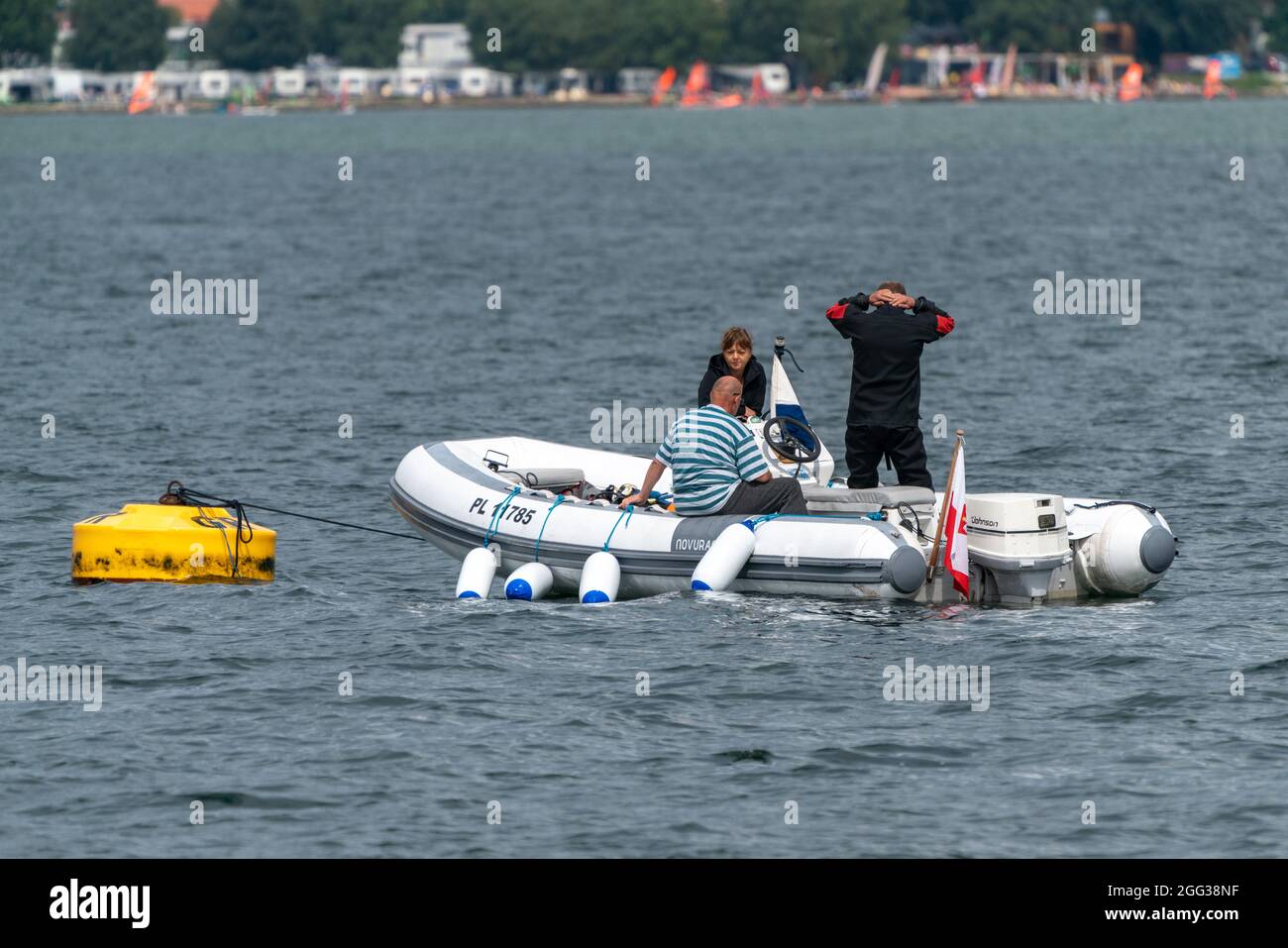 Jastarnia, Pologne - 08.01.2021: Plongeur mâle portant jusqu'au néoprène noir, debout sur un petit bateau à moteur blanc attaché à la bouée jaune près de la Baltique Banque D'Images