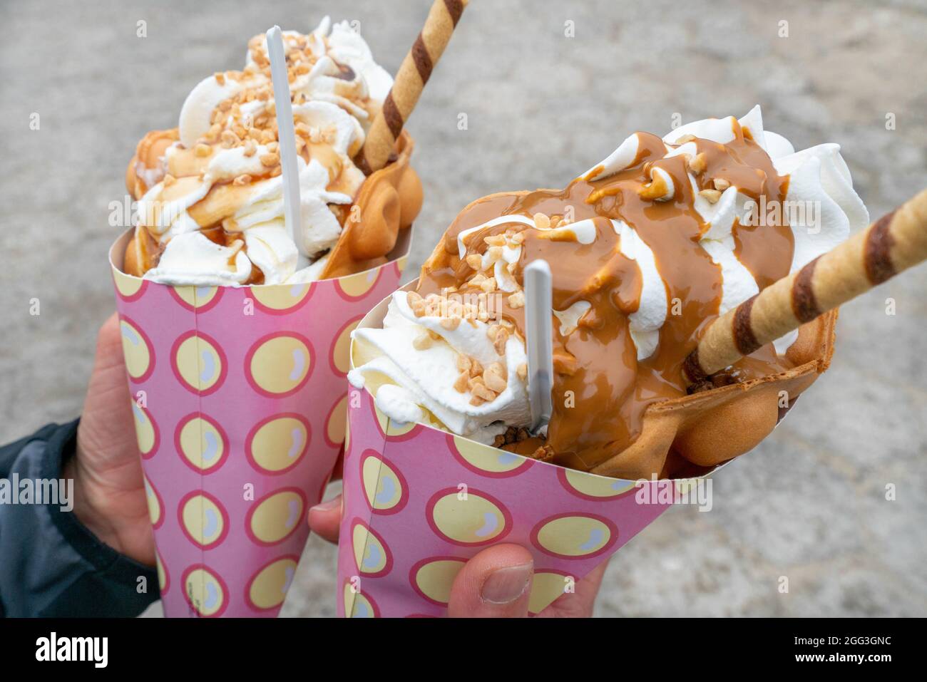 Gros plan en plein air de deux gaufres à bulles, un bagelkowe de gofry, avec beaucoup de crème glacée dans des cônes de papier rose. Célèbre dessert de Pologne. Une douceur massive Banque D'Images