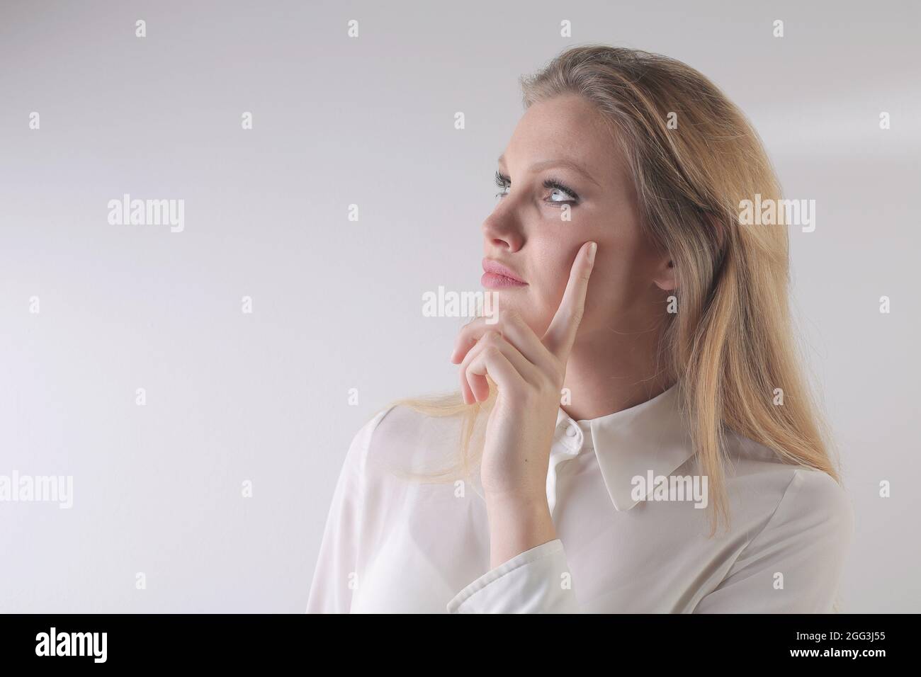 Portrait d'une belle femme blonde pensant et regardant vers le haut sur un fond blanc Banque D'Images