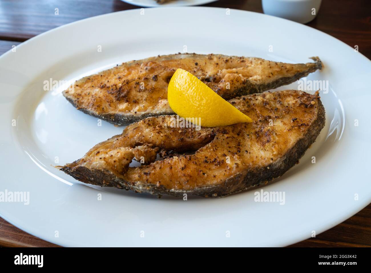 Gros plan de filets de flétan fraîchement frits au citron sur une assiette blanche dans un pub local de Jastarnia, Pologne. Les fruits de mer polonais de la Baltique Banque D'Images
