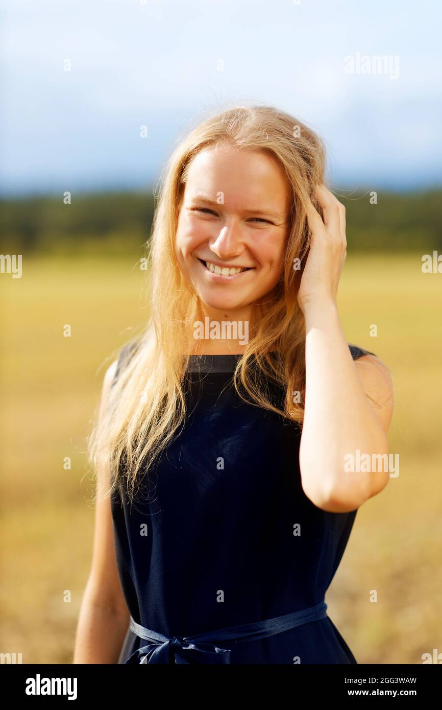Portrait d'une jeune fille souriante contre terrain sur fond flou par un beau jour d'été Banque D'Images Portrait d'une jeune fille souriante contre terrain sur fond flou par un beau jour d'été Banque D'Images