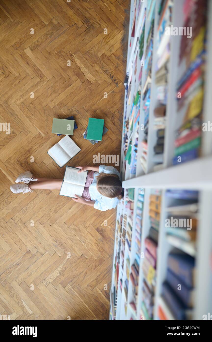 Un élève lit un livre à l'étage de la bibliothèque Banque D'Images