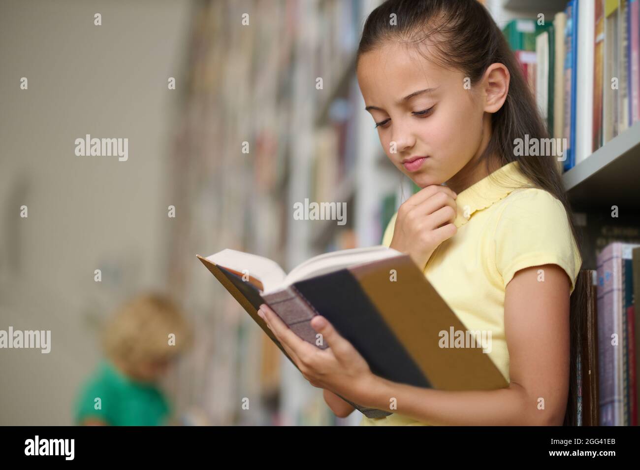 Une écolière sérieuse s'est concentrée sur la lecture d'un livre Banque D'Images